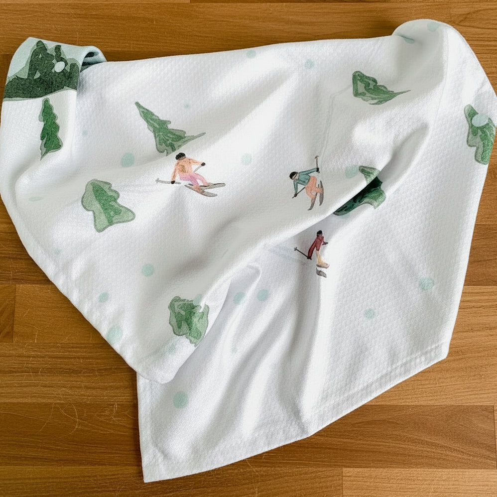 White towel with green trees and skiers on a wooden surface