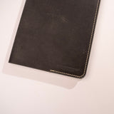 Black leather notebook with visible brand name on a white background