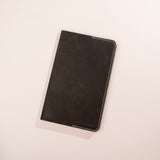 Black leather notebook on a light beige background