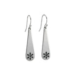 Pair of silver teardrop earrings with snowflake designs on a wooden surface