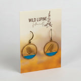 Earrings on a Wild Lupine Folkcraft branded card with a gradient background
