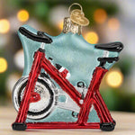 Glass ornament shaped like a bicycle with a red frame on a white background