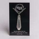 Silver pendant necklace on a black card with branding and contact information.