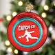 Decorative ornament with 'Catch It!' text and a silhouette of a person catching a disc on a red background.