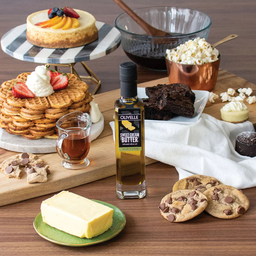 Table with various desserts, a bottle of olive oil, and cookies on a wooden surface.