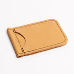 A minimalist tan leather money clip wallet with black contrast stitching, shown on a clean white background.