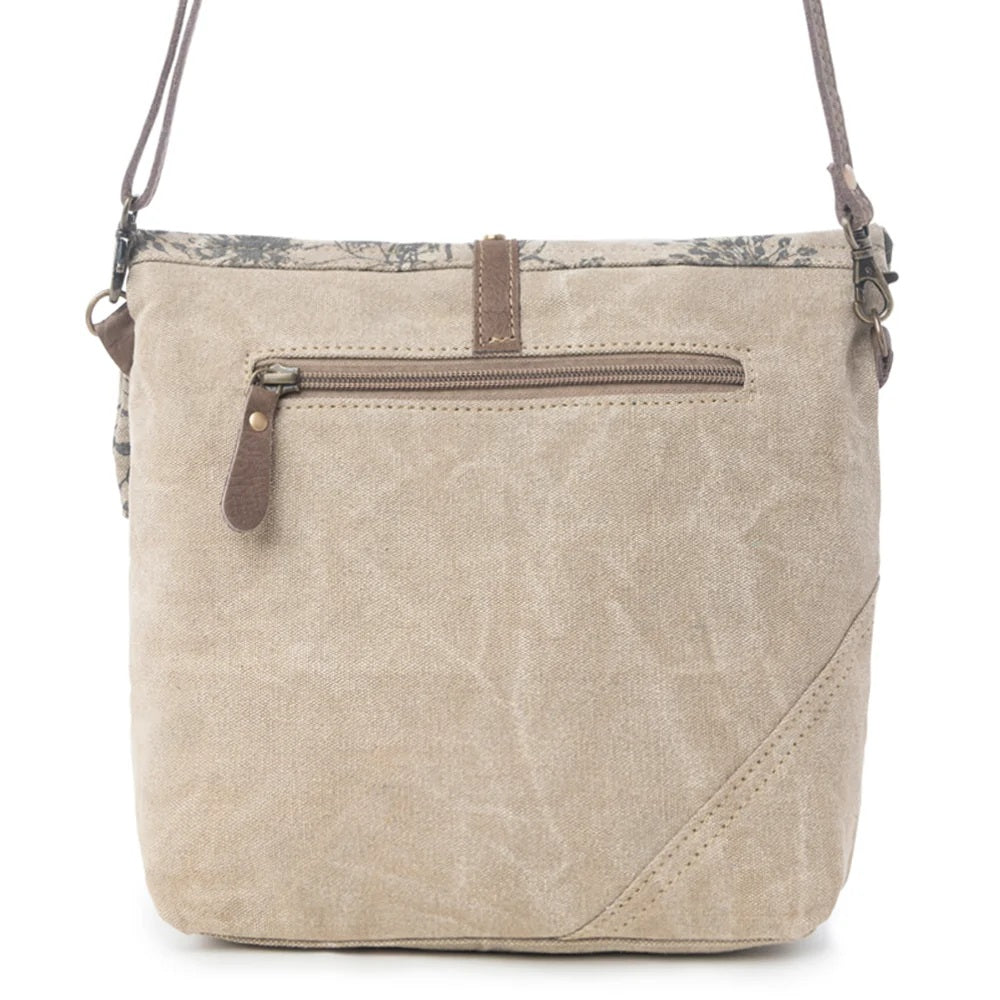 A beige canvas crossbody bag with brown leather accents, a front zippered pocket, and a floral patterned top trim, shown against a plain white background.