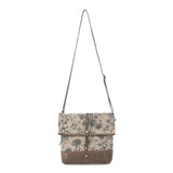 A canvas shoulder bag with a brown floral print and brown leather trim, featuring a long adjustable shoulder strap and a front flap closure with metal snap details, shown against a plain white background.