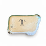 Back of a rectangular ceramic tray with a rustic, hand-painted finish, featuring a turquoise glaze on the top half, a white textured glaze on the bottom half, and a dark brown crackled border. The tray is displayed on a dark wood tabletop.