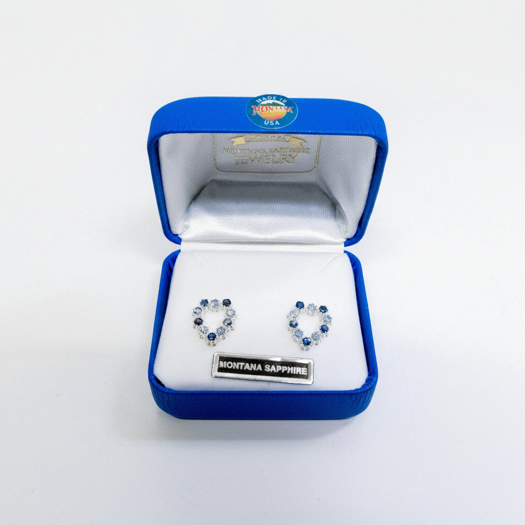 Heart-shaped earrings in a blue jewelry box with 'Montana Sapphire' label.