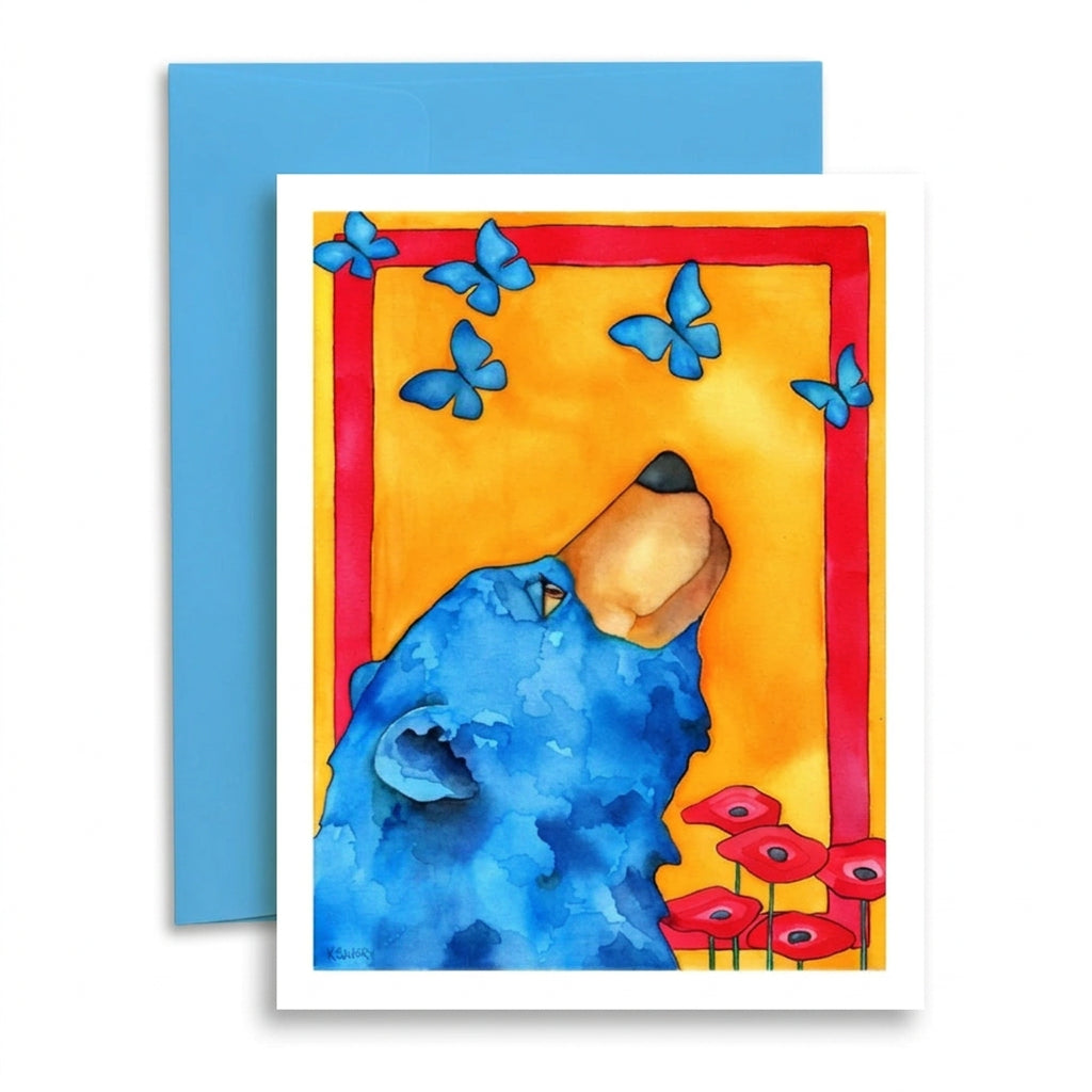 A square art print or greeting card featuring a watercolor-style blue bear looking upward, with blue butterflies, a red border, and red flowers on a yellow background. A blue envelope is placed behind the card on a white studio background.
