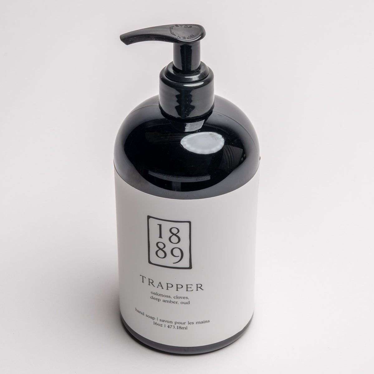 A 1889 brand Trapper hand cream bottle with a glossy black body and pump dispenser, featuring a white label with black text, set against a clean white background.