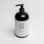 A black pump bottle with a white label for 1889 Trapper Hand & Body Wash, photographed on a clean white background.
