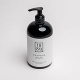 A black pump bottle with a white label for 1889 Trapper Hand & Body Wash, photographed on a clean white background.
