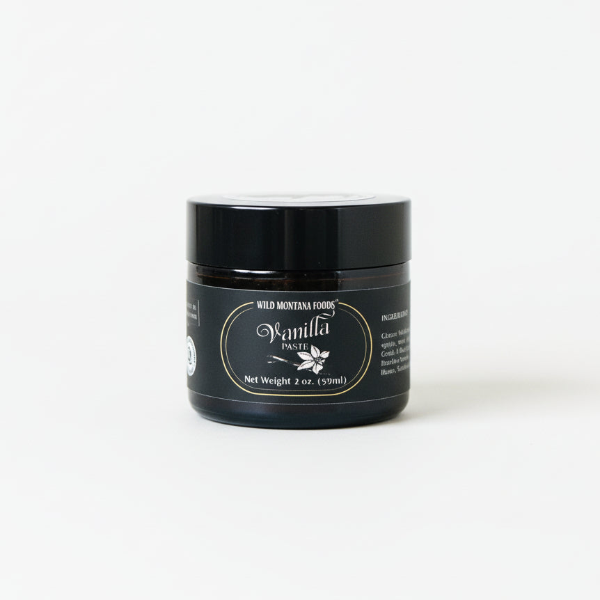 Black jar of wild montana foods vanilla paste with a label on a white surface