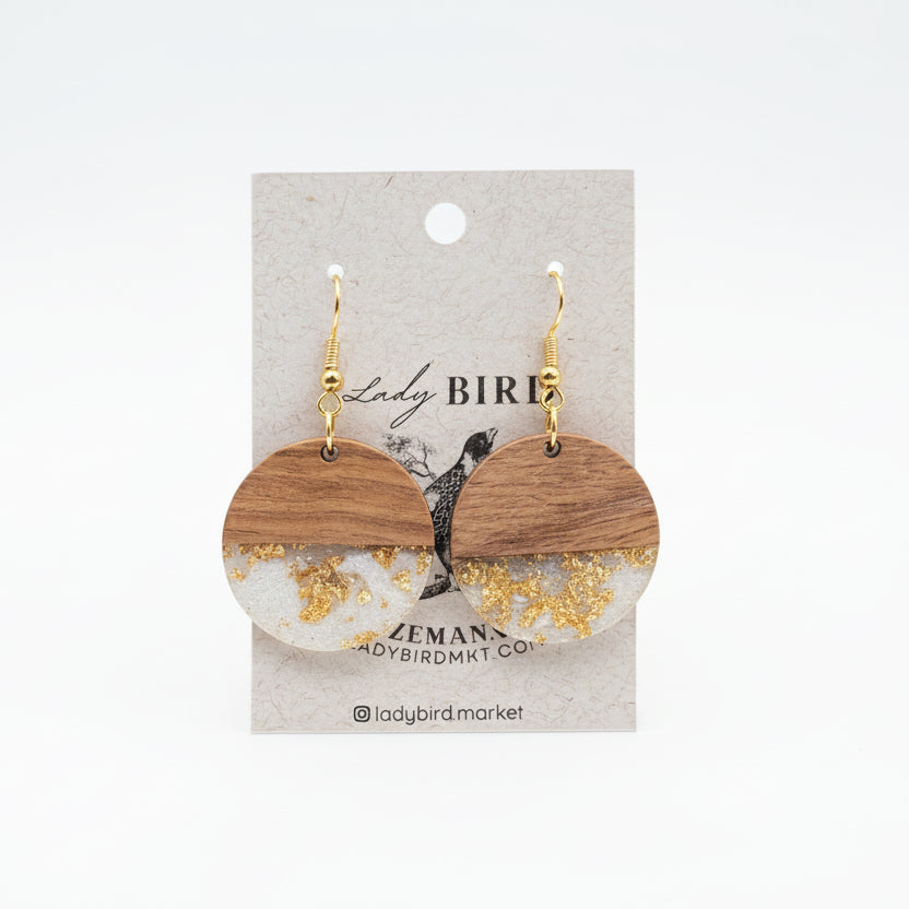 Wooden earrings with gold accents on a branded card, placed on a white surface.