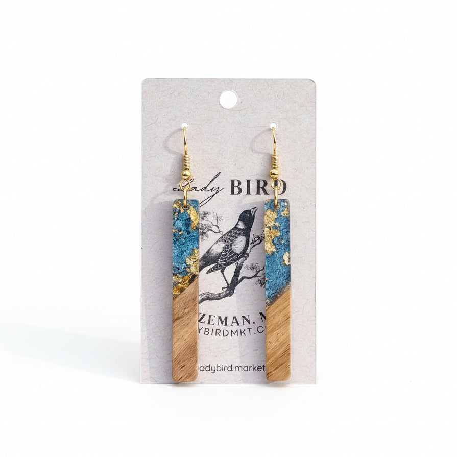 Wooden and blue earrings on a branded card with a white background