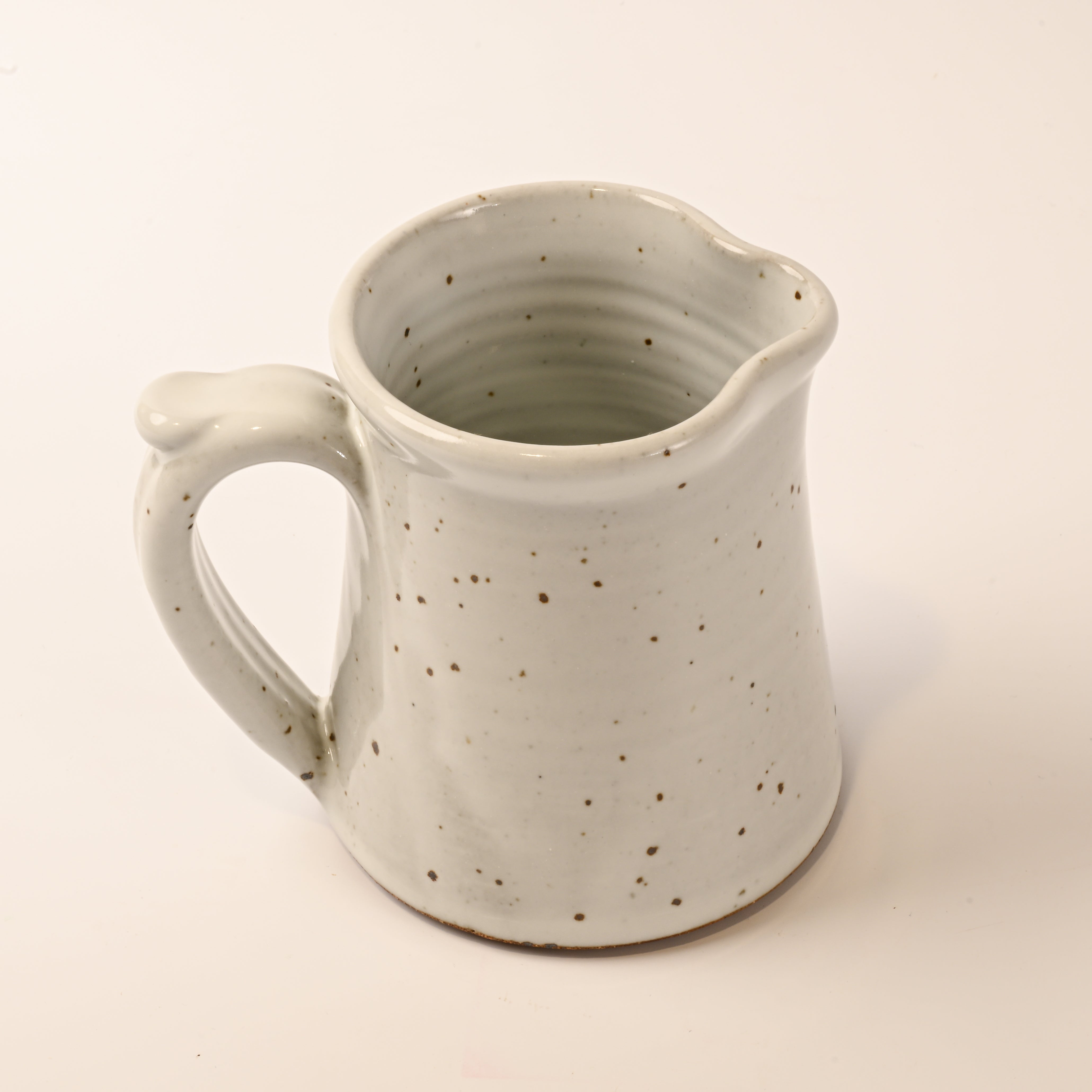 Speckled ceramic pitcher on a beige background