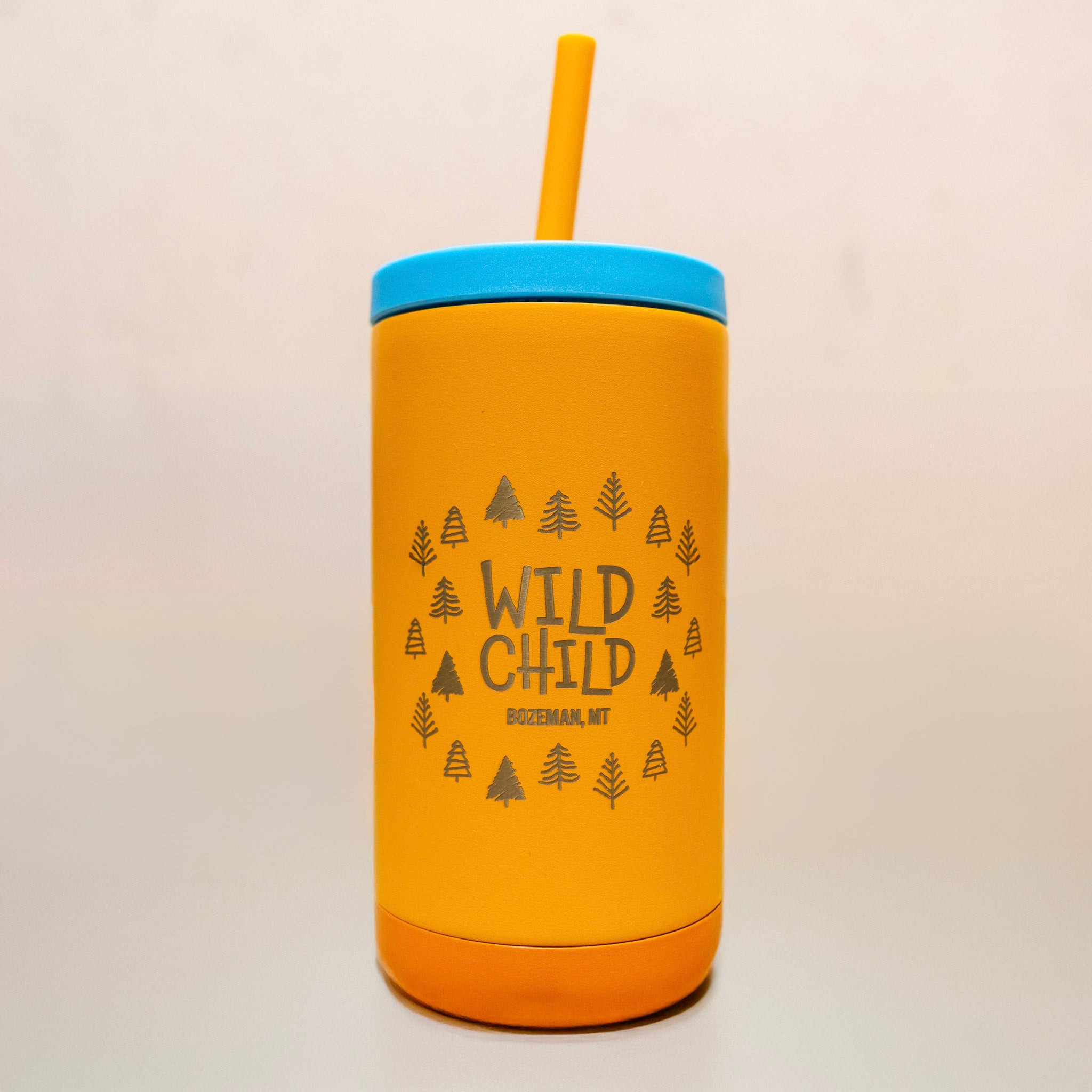 Yellow tumbler with blue lid and straw on a wooden surface