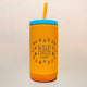 Yellow tumbler with blue lid and straw on a wooden surface