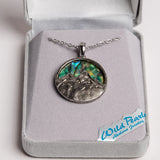 A silver pendant necklace featuring a mountain landscape design over an iridescent abalone shell inlay, displayed inside a gray jewelry box. A 'Wild Pearls Abalone Jewelry' brand tag is visible on the box.