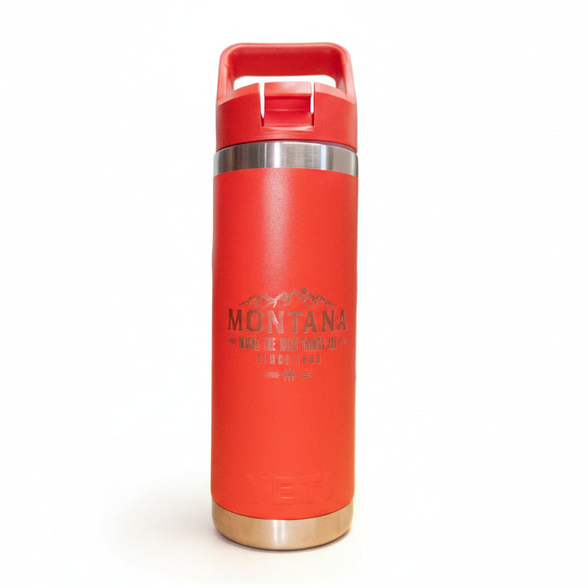 Red insulated bottle with 'Montana' branding on a wooden surface.