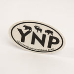 An oval Yellowstone National Park sticker featuring black silhouettes of a bear, moose, and bison above the large letters 'YNP', with 'YELLOWSTONE NATIONAL PARK' curved along the bottom border, shown on a clean white background.