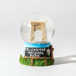 Snow globe with a miniature replica of the Arch at Yellowstone National Park on a white background