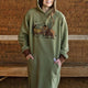 Person wearing a green hoodie with a bison design in front of a wooden background