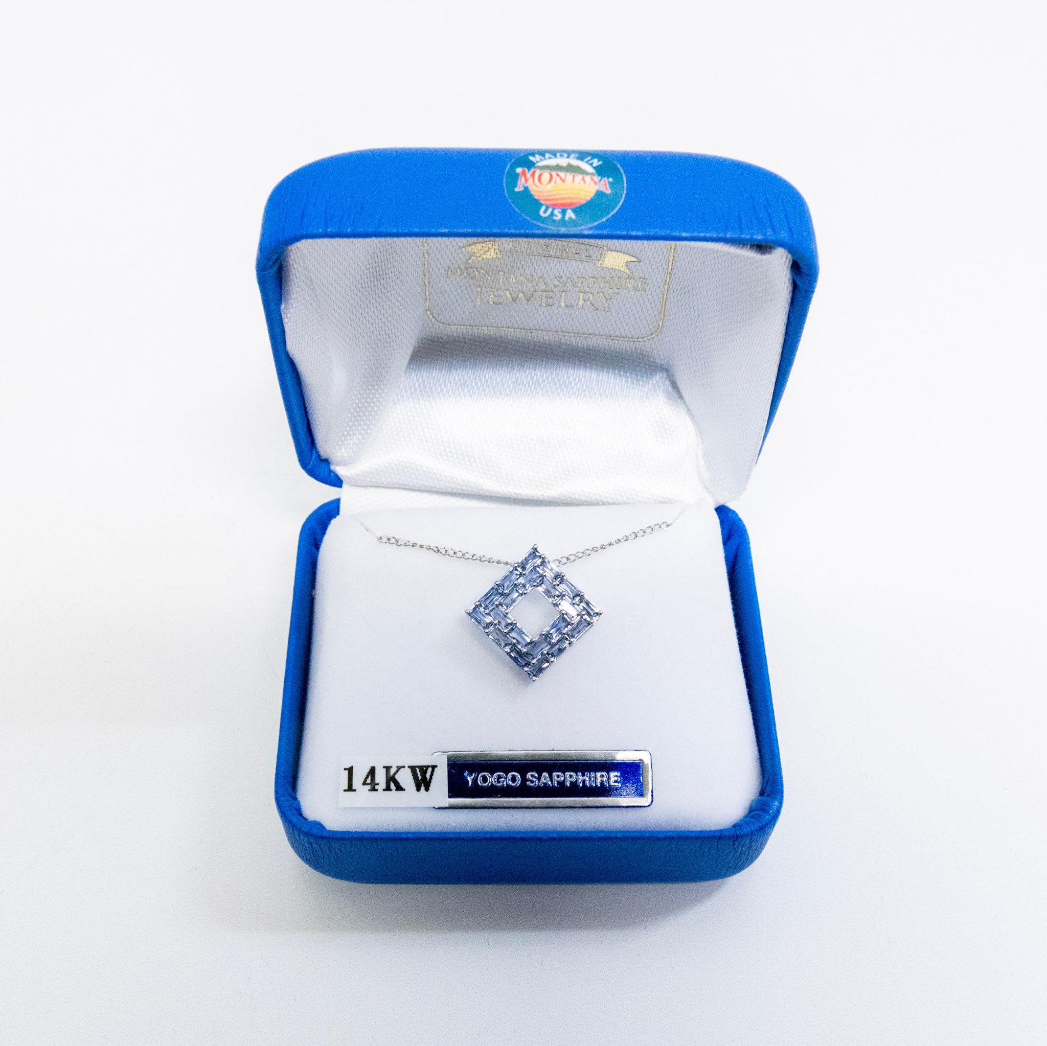 Yogo sapphire necklace in a blue jewelry box with 'Yogo Sapphire' label on a white background