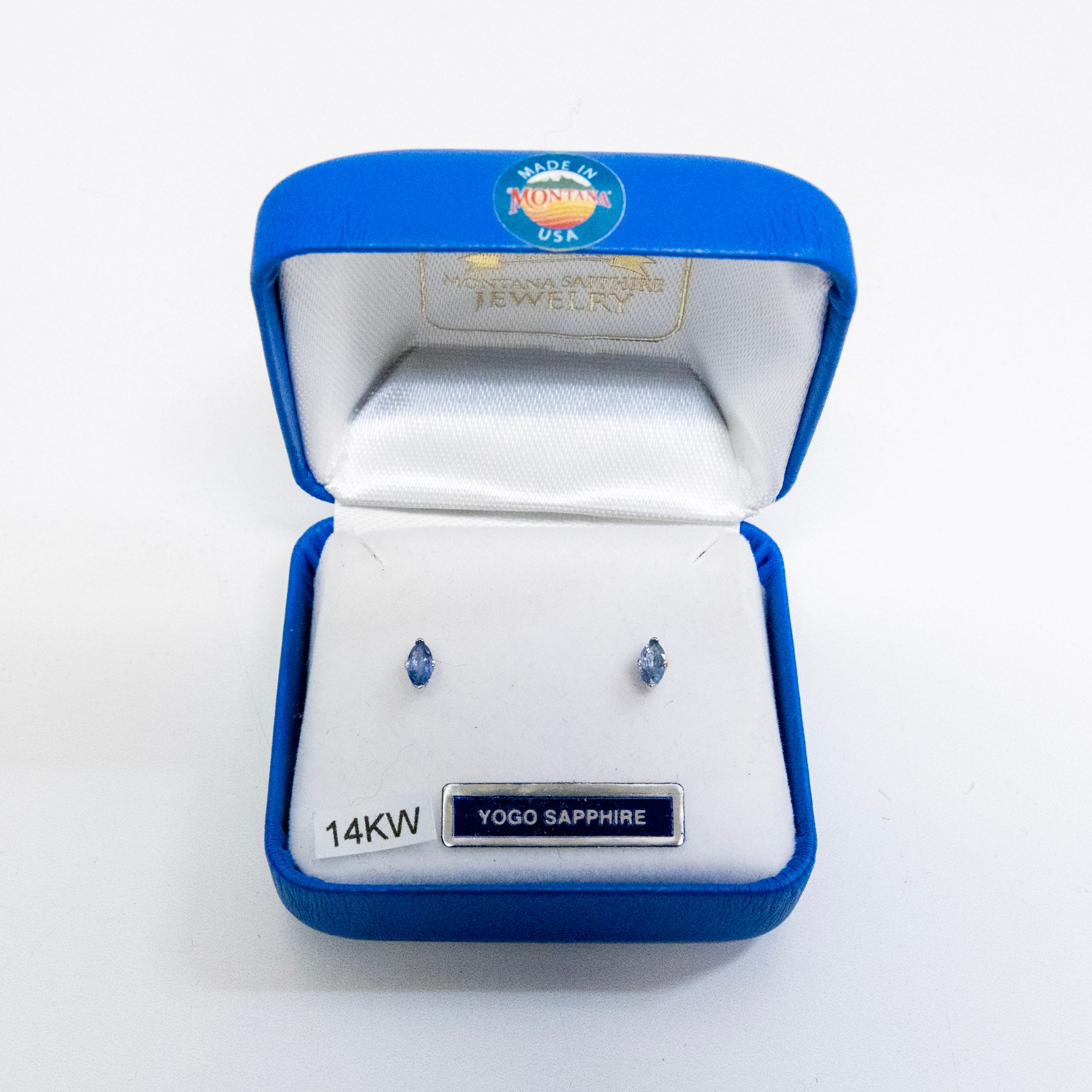 Yogo Sapphire earrings in a blue jewelry box on a white background