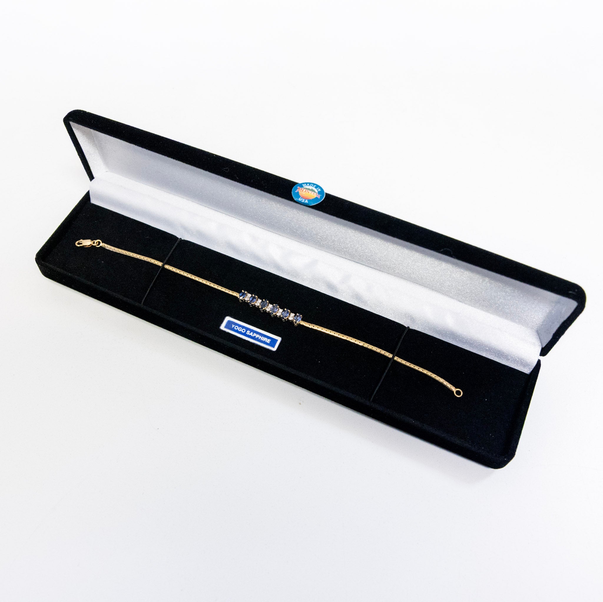 Gold bracelet with sapphires in a black box on a white background