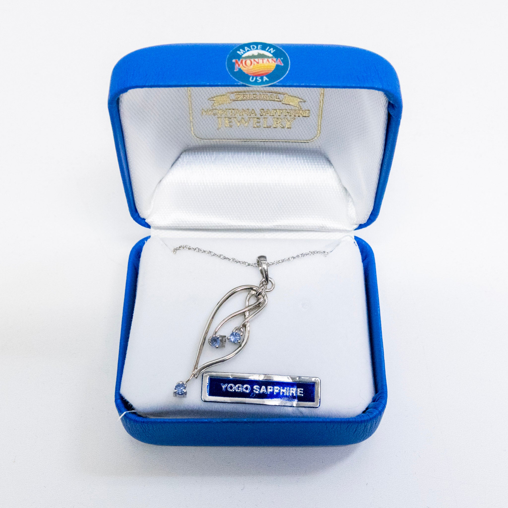 Silver necklace with 'Yoga Sapphire' pendant in a blue and white jewelry box.