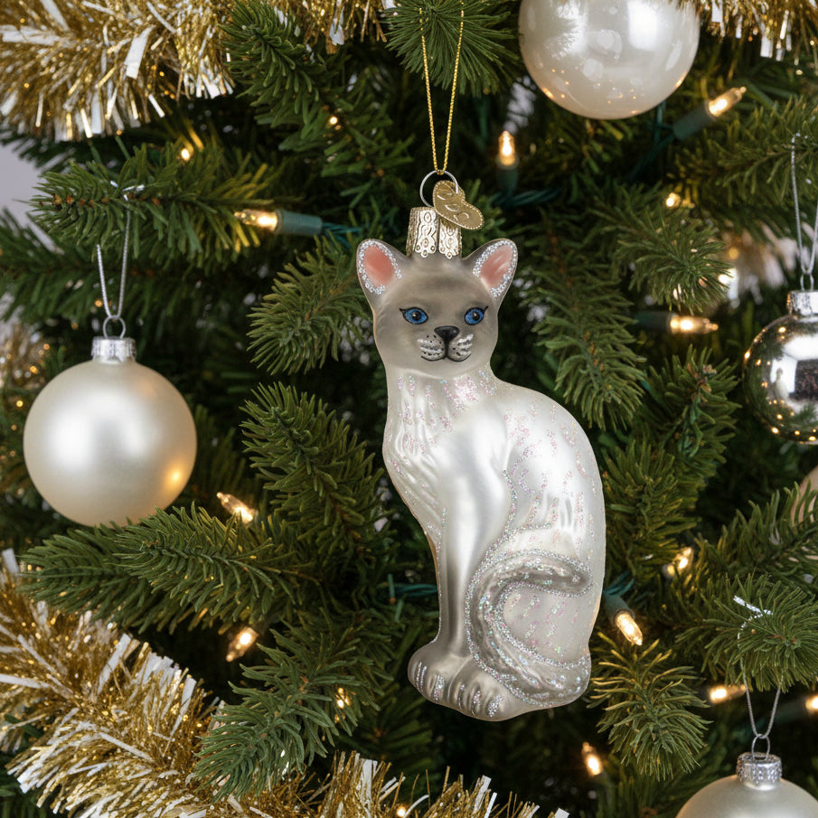 Glass ornament of a Siamese cat with blue eyes on a white background