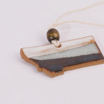 Ceramic ornament shaped like a state with a rope and bead on a white background