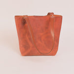 Brown leather tote bag on a light beige background