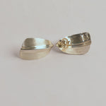 Two sterling silver earrings on a gray background 