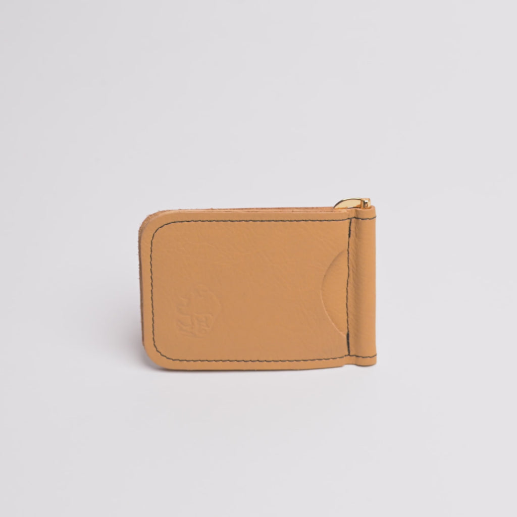 A tan leather money clip wallet with gold-tone metal hardware, black contrast stitching, and an embossed lion logo on the front, shown on a clean white background.