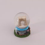 Snow globe with a miniature replica of the Arch at Yellowstone National Park on a white background