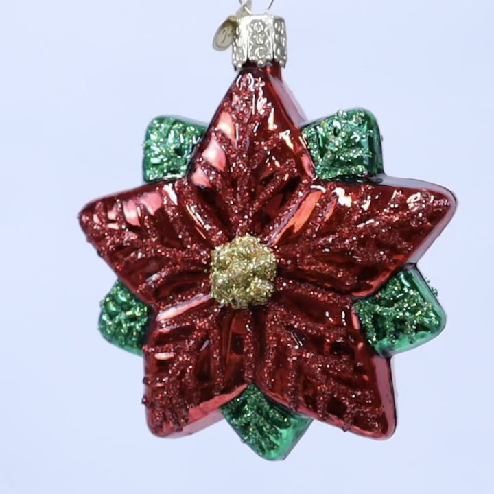 Red and green glass flower ornament on a white background