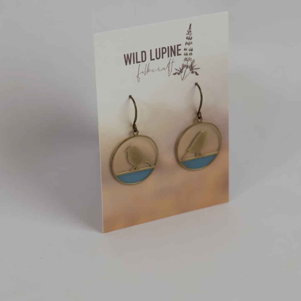 Earrings on a Wild Lupine Folkcraft branded card with a gradient background