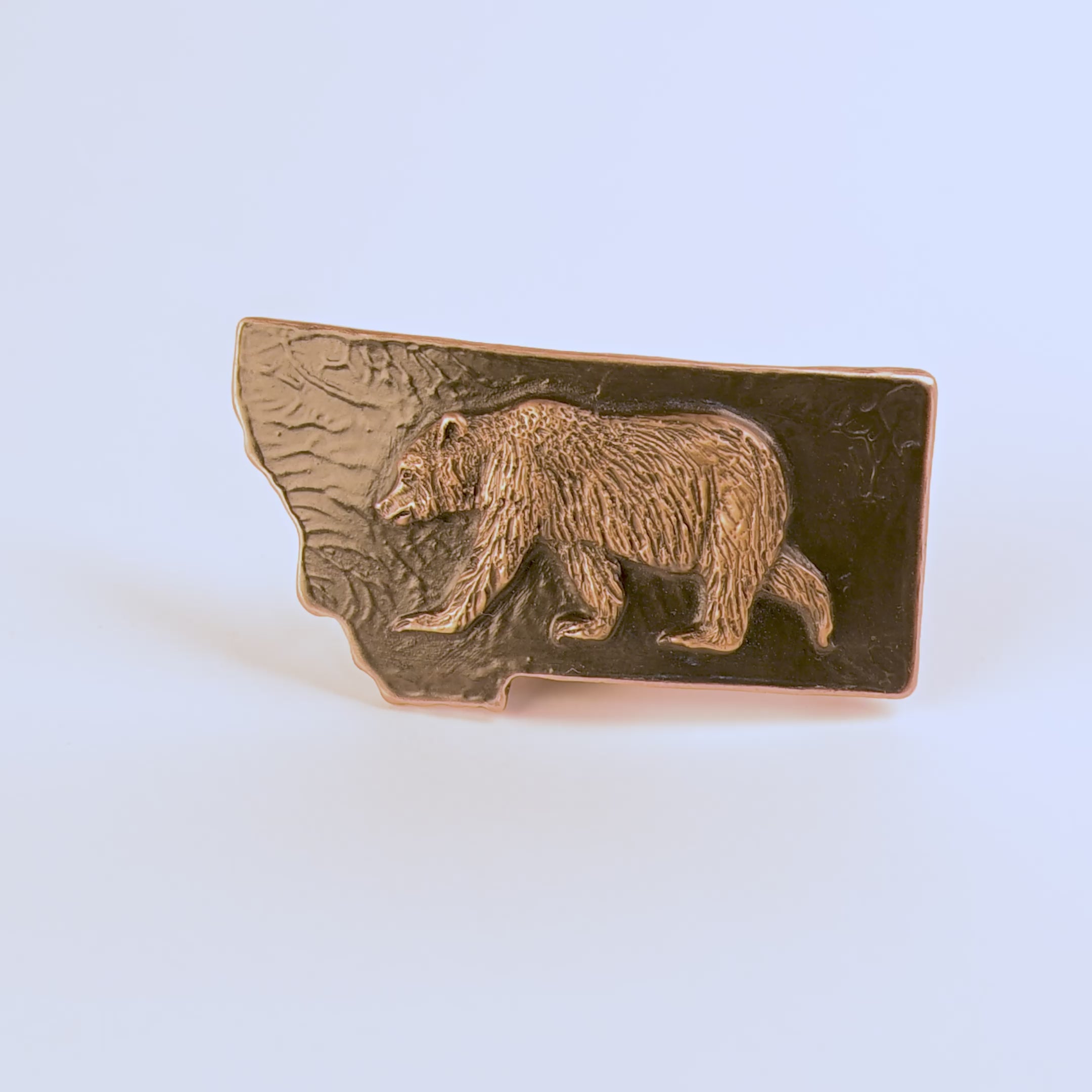 Metallic bear emblem belt buckle on a black background