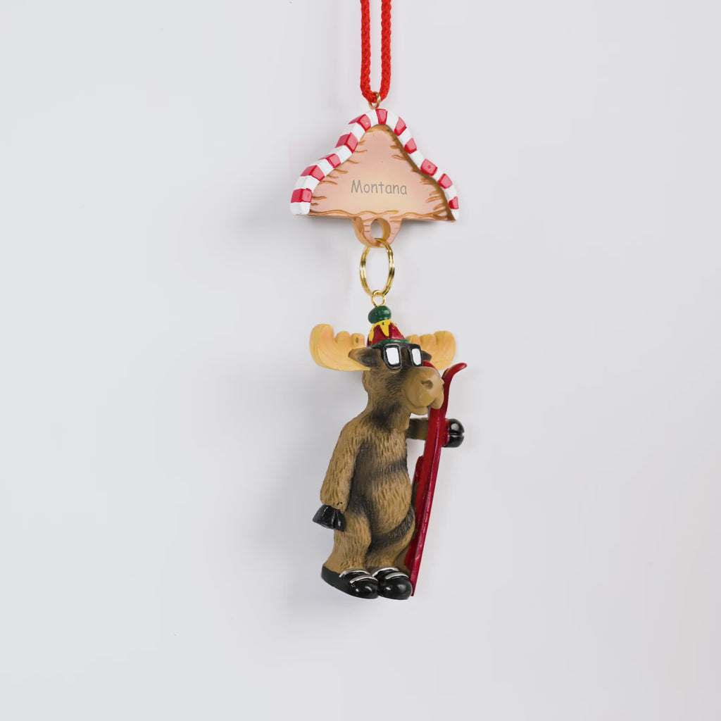 Moose ornament with skis and 'Montana' hat on a white background