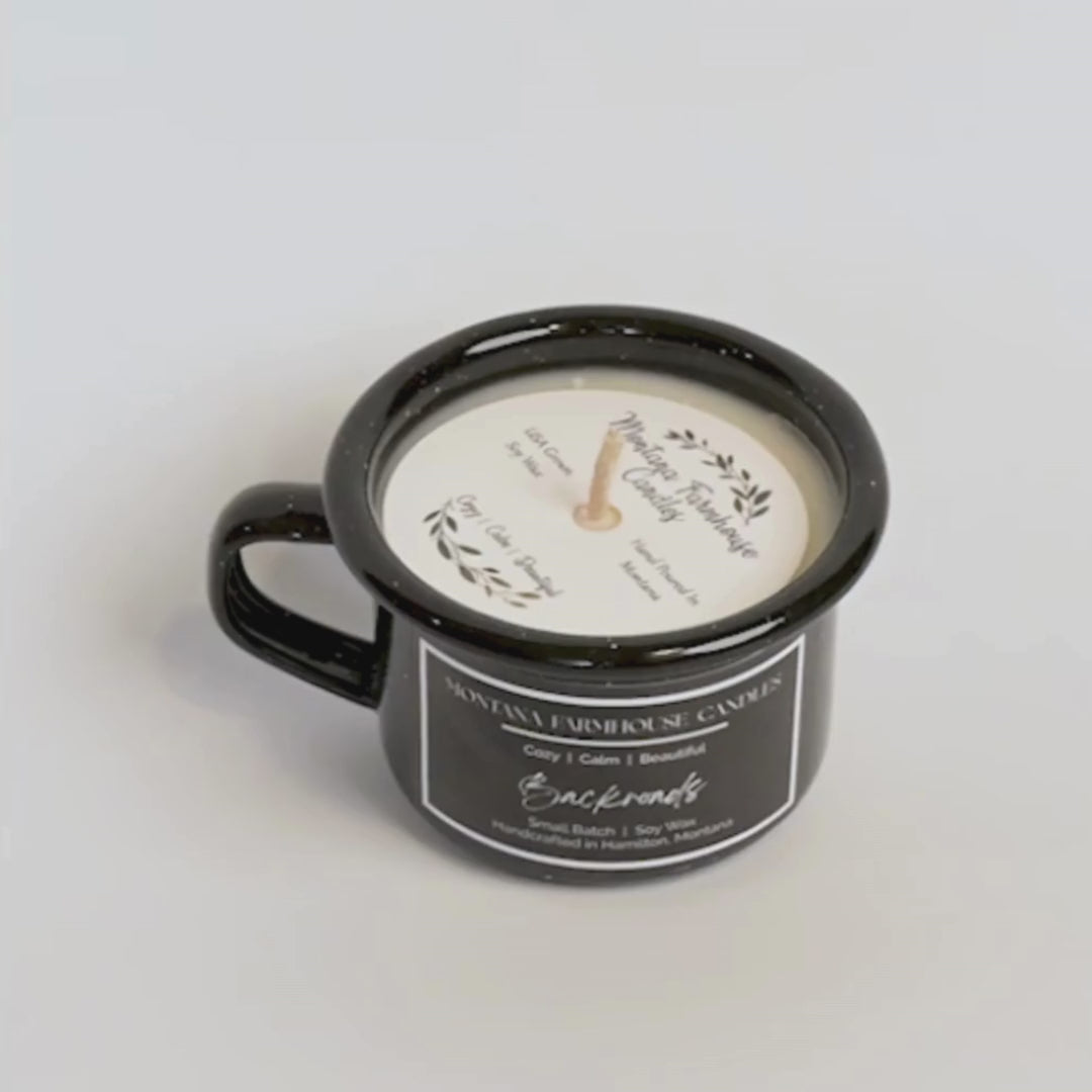 Black mug with a candle labeled 'Montana Farmhouse Candles' on a light gray background