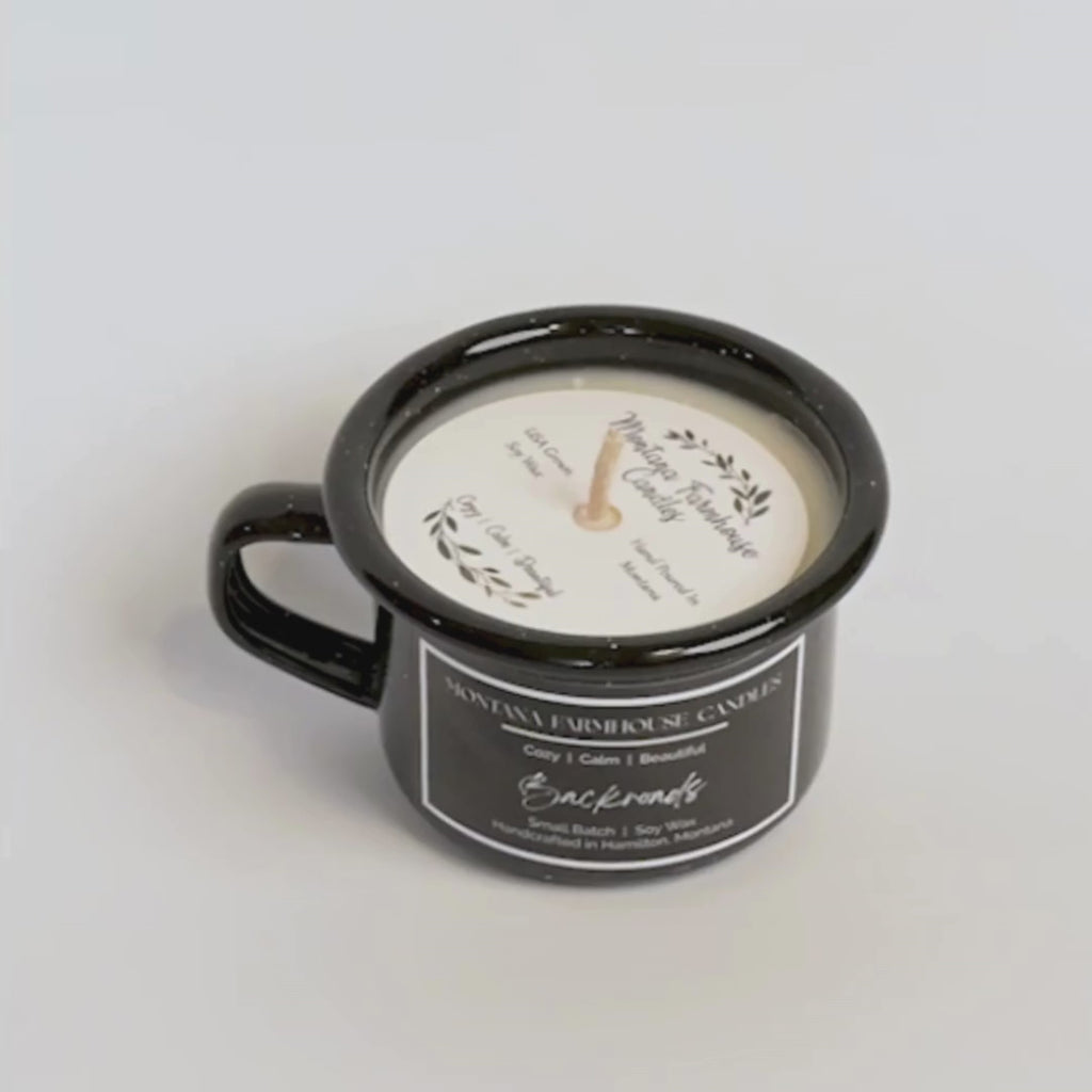 Black mug with a candle labeled 'Montana Farmhouse Candles' on a light gray background