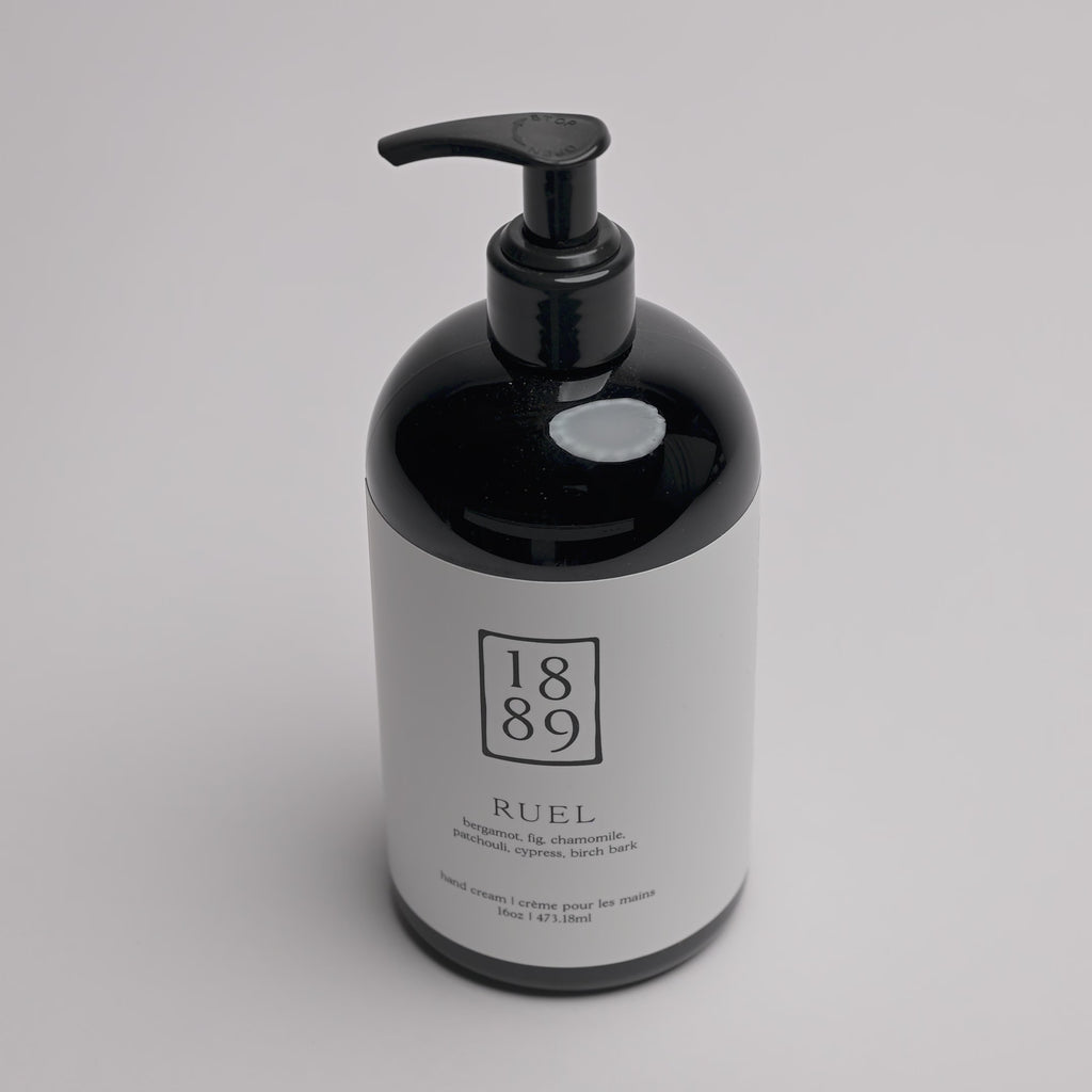 A black pump bottle of RUEL hand cream with a white label, photographed on a clean white background.