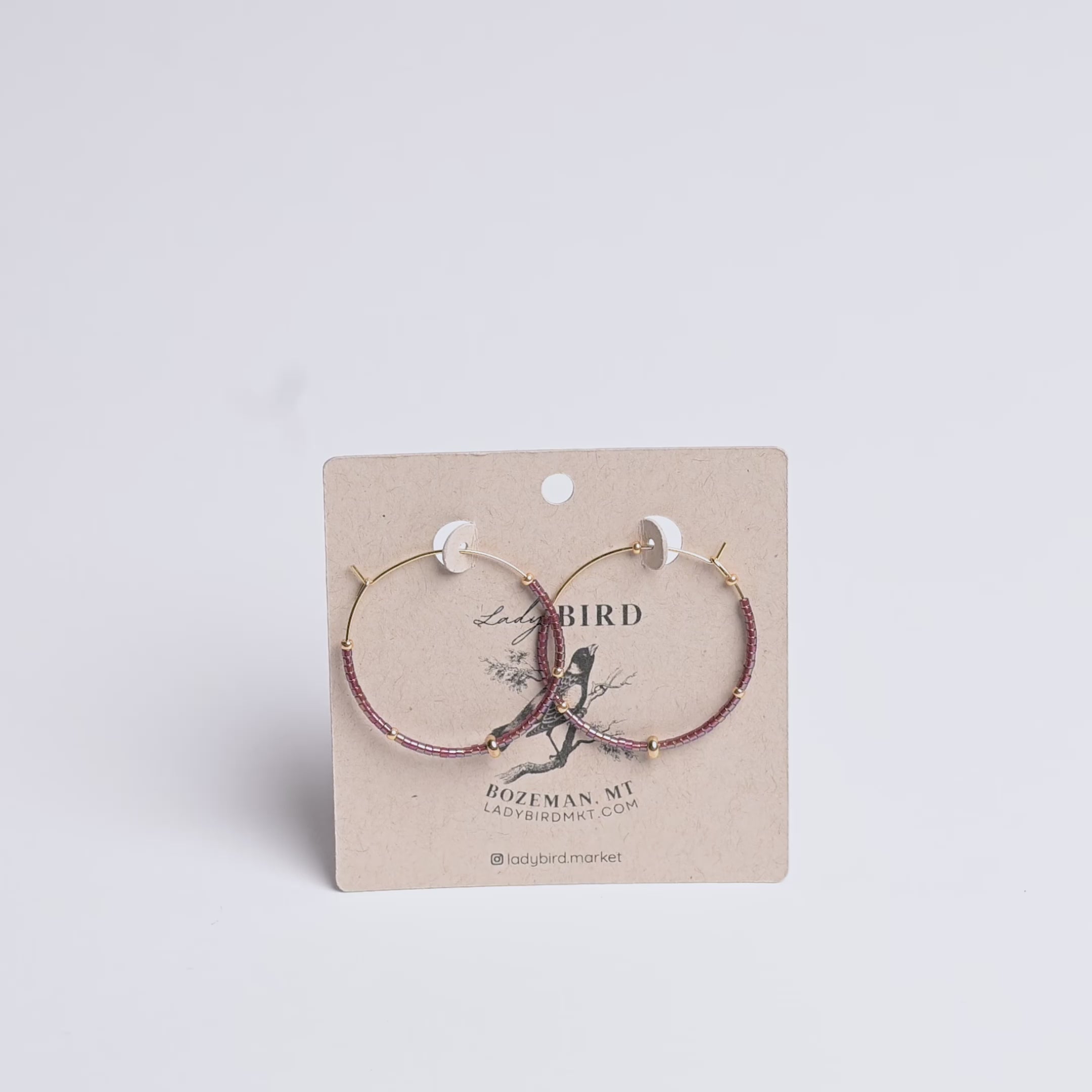 Two hoop earrings on a Lady Bird branded card with a white background