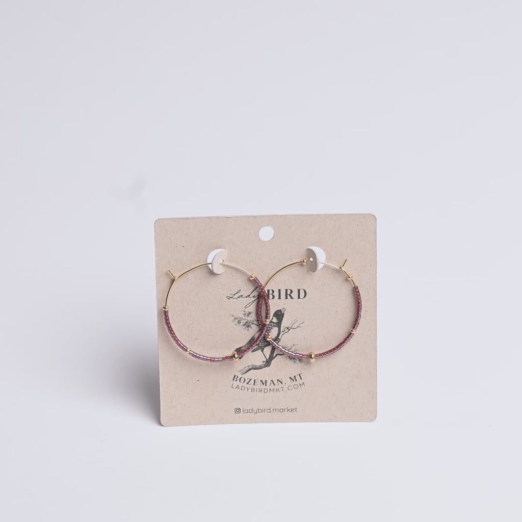 Two hoop earrings on a Lady Bird branded card with a white background