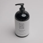 A black pump bottle with a white label for 1889 Trapper Hand & Body Wash, photographed on a clean white background.