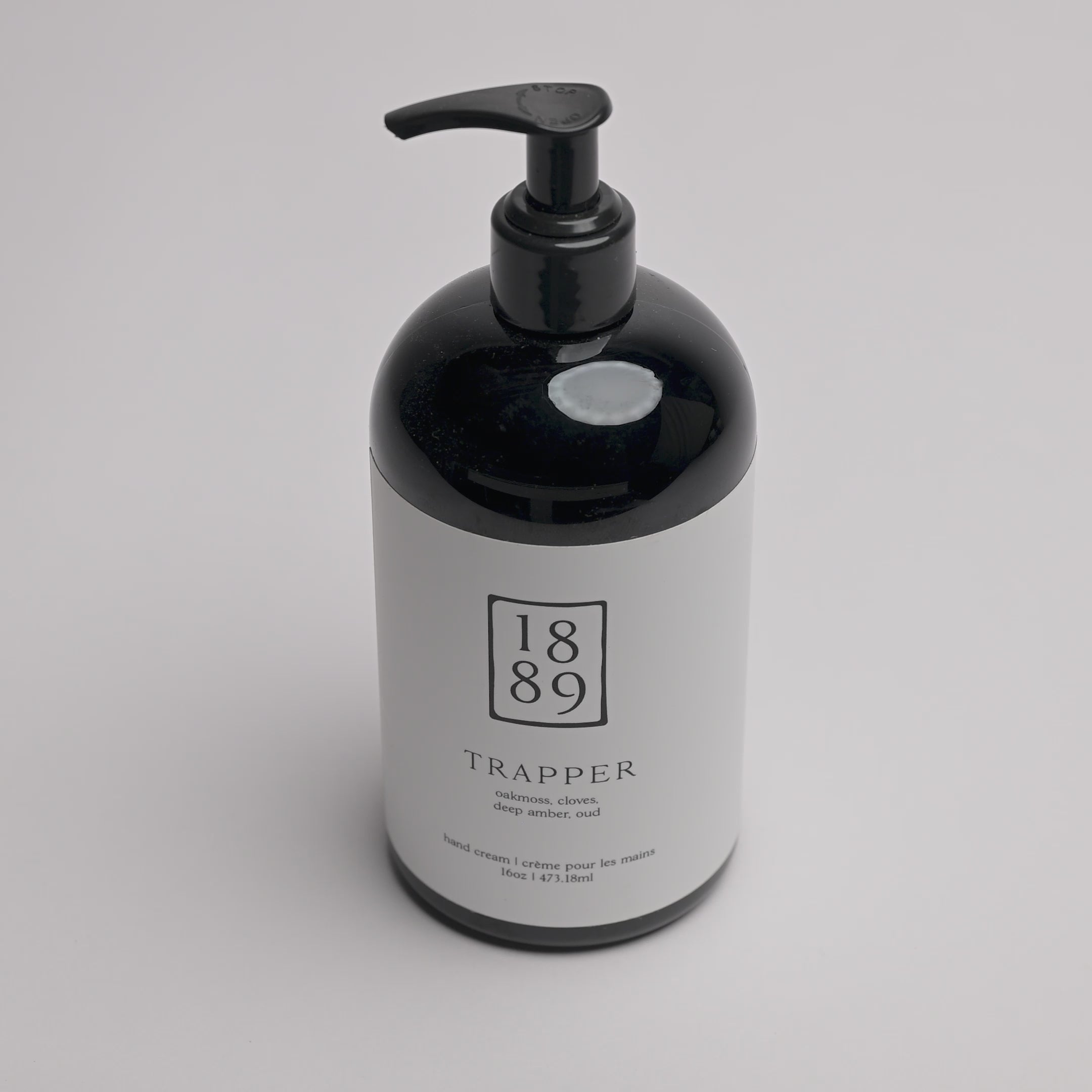 A black pump bottle with a white label for 1889 Trapper Hand & Body Wash, photographed on a clean white background.